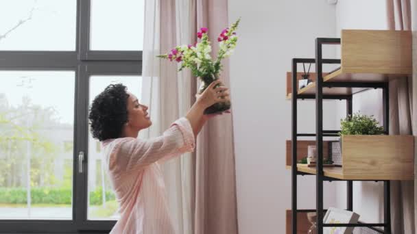 Donna mettendo fiori sulla scaffalatura a casa — Video Stock