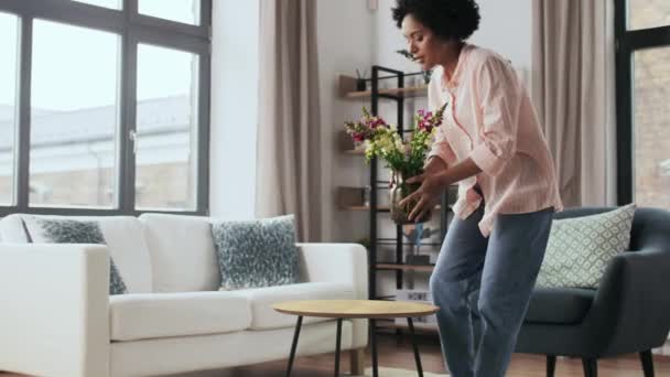 Vrouw plaatst bloemen op salontafel thuis — Stockvideo