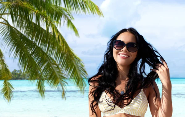 Χαμογελαστή νεαρή γυναίκα με γυαλιά ηλίου στην καλοκαιρινή παραλία — Φωτογραφία Αρχείου