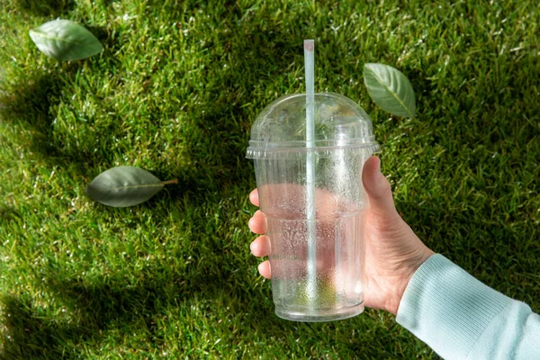 Gros plan de la main enlever la tasse en plastique de l'herbe — Photo