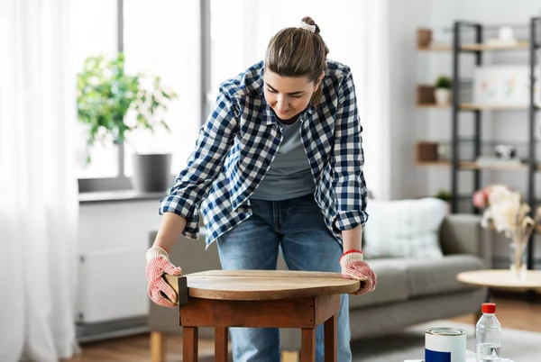 Жінка шліфує старий круглий дерев'яний стіл губкою — стокове фото