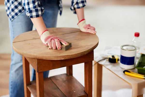 Женщина шлифует старый круглый деревянный стол с губкой — стоковое фото