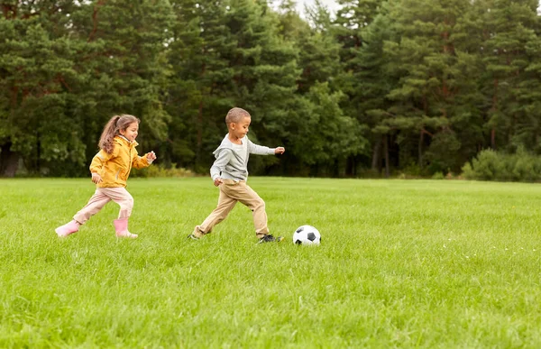 Маленькие дети с мячом играют в футбол в парке — стоковое фото