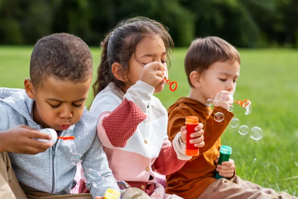 Grupp av barn blåser såpbubblor i parken — Stockfoto