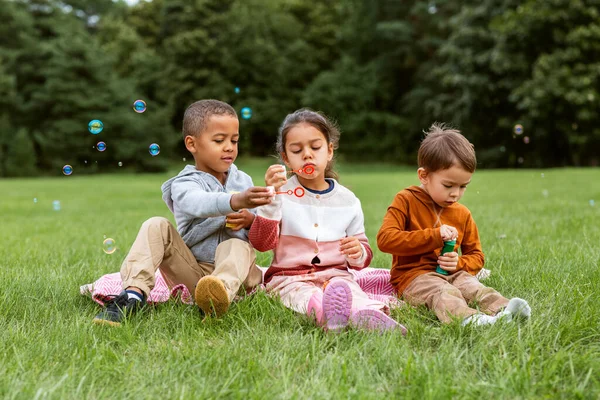 Kindergruppe pustet Seifenblasen im Park — Stockfoto