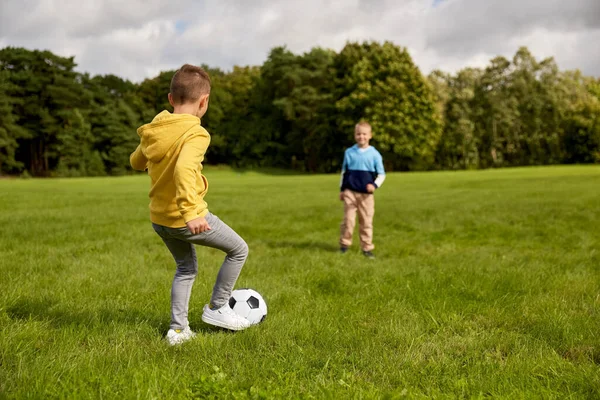 Niños pequeños felices con pelota jugando al fútbol en el parque —  Fotos de Stock