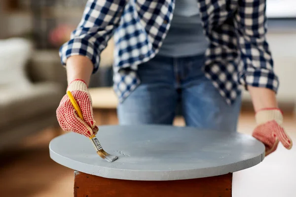 Woman painting old wooden table in grey color Imagens Royalty-Free