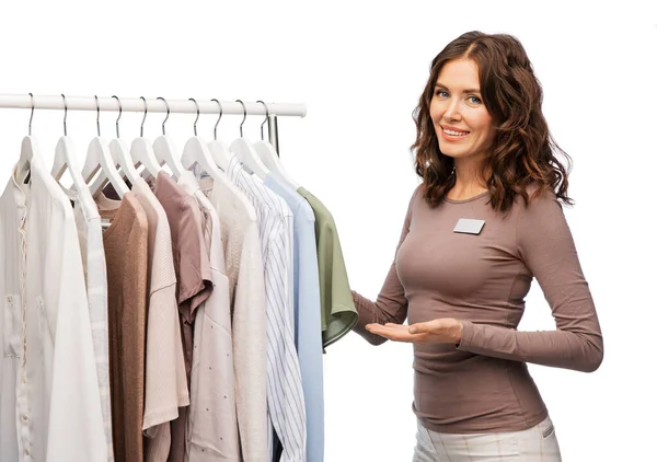 Asistente de tienda femenina feliz con ropa en percha —  Fotos de Stock