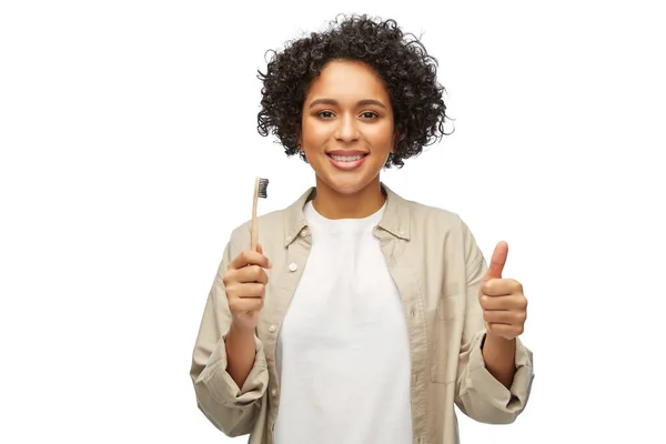 Mujer sonriente sosteniendo cepillo de dientes de madera —  Fotos de Stock