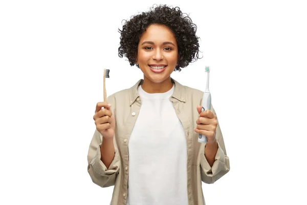 Žena porovnávající dřevěné a elektrické zubní kartáčky — Stock fotografie