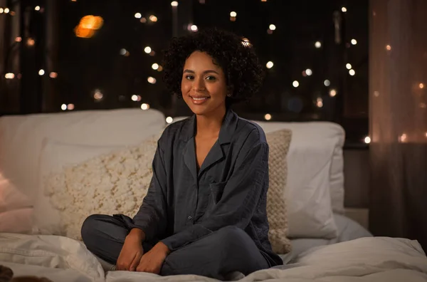 Mulher feliz em pijama sentado na cama à noite — Fotografia de Stock