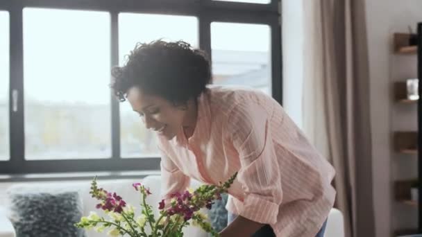 Mulher colocando flores na mesa de café em casa — Vídeo de Stock