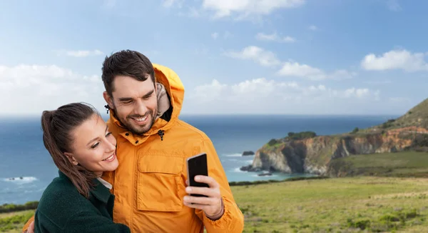 Pareja con teléfono inteligente sobre la costa en California — Foto de Stock