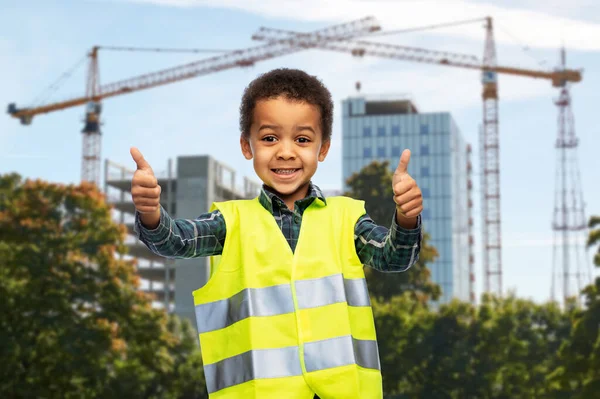 Menino feliz em colete de segurança mostrando polegares para cima — Fotografia de Stock