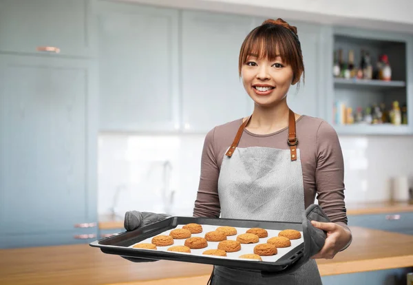 Mujer feliz con galletas en la bandeja del horno en la cocina — Foto de Stock