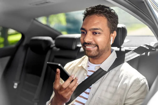 Passageiro com fones de ouvido e celular em táxi — Fotografia de Stock