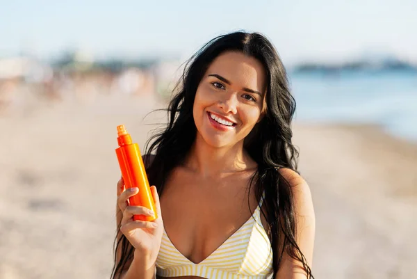 Donna sorridente in bikini con crema solare sulla spiaggia — Foto Stock