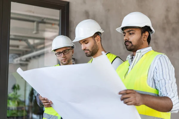 Architects in helmets with blueprint at office — Stock Photo, Image