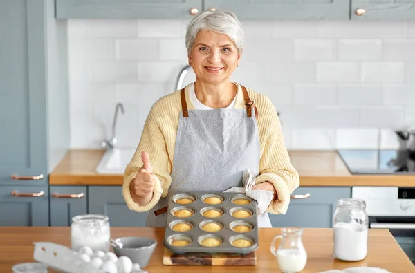 Женщина с кексами в выпечке плесени на кухне — стоковое фото