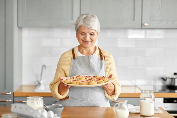Жінка тримає тарілку з кексами на кухні — стокове фото