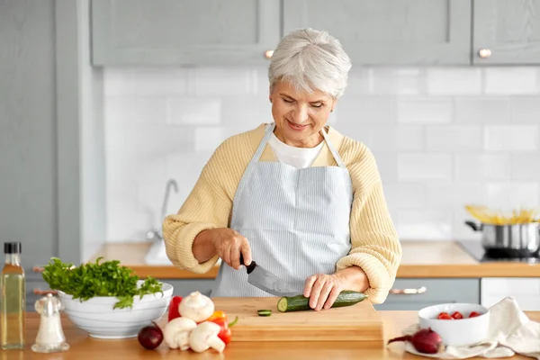Щаслива жінка ріже огірок на кухні — стокове фото