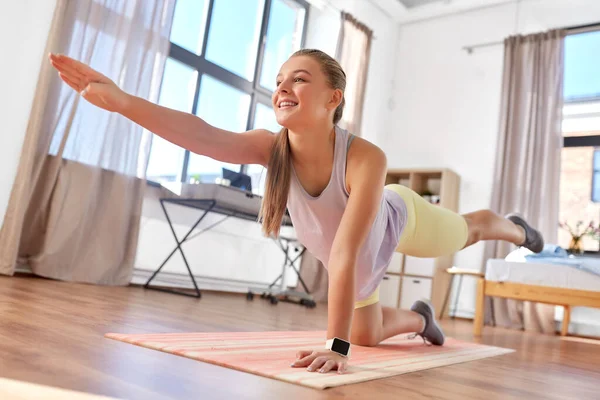 Šťastný dospívající dívka cvičení na jóga mat doma — Stock fotografie