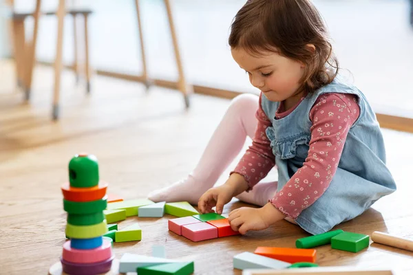 Menina feliz brincando com blocos de brinquedo em casa — Fotografia de Stock