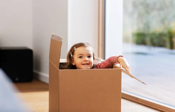 Petite fille assise dans une boîte en carton à la maison — Photo