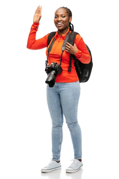 Χαρούμενη γυναίκα με κάμερα και σακίδιο που κουνάει το χέρι — Φωτογραφία Αρχείου