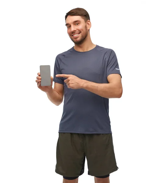 Улыбающийся мужчина в спортивной одежде, показывающий смартфон — стоковое фото