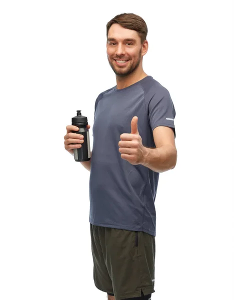 Smiling man with sports bottle showing thumbs up — Stock Photo, Image