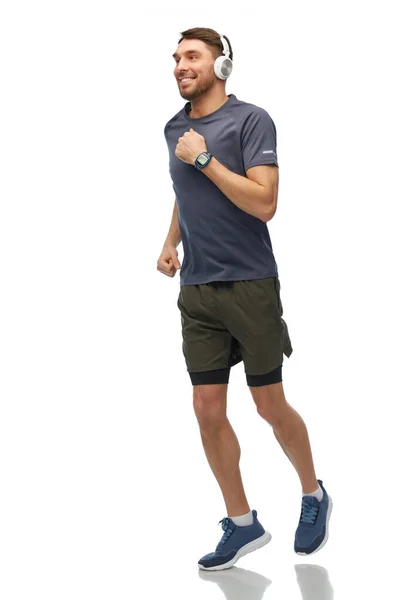 Úsměv běžící muž ve sluchátkách s chytrými hodinkami — Stock fotografie