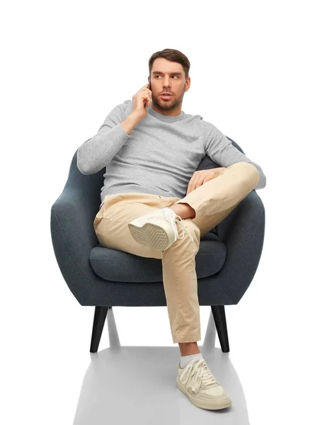 Mężczyzna siedzi w fotelu i dzwoni na smartfona — Zdjęcie stockowe