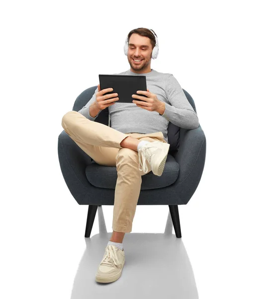 Человек с наушниками и планшетным компьютером, сидящий в кресле — стоковое фото
