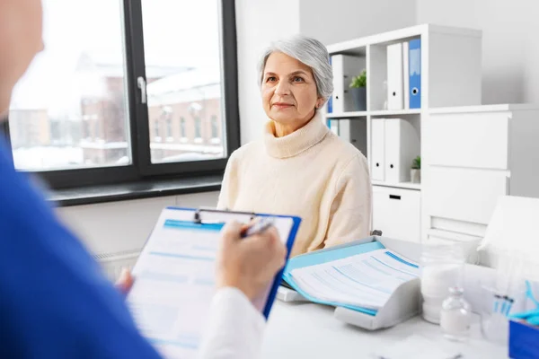 Arzt mit Klemmbrett und Seniorin im Krankenhaus — Stockfoto