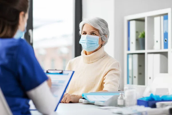 Médecin avec presse-papiers et femme âgée à l'hôpital — Photo