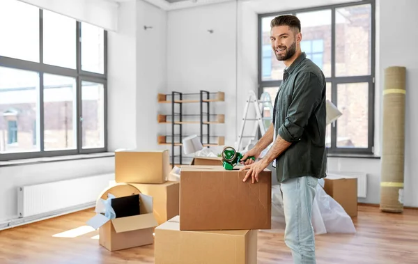 Muž s lepicí páskou balení box v novém domově — Stock fotografie