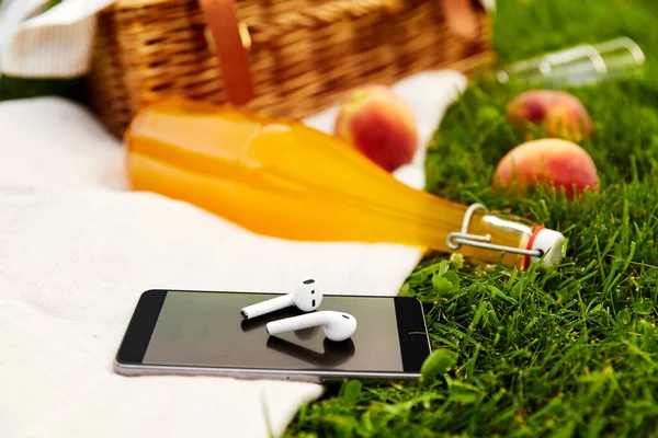 Teléfono, auriculares, cesta de picnic y botella de jugo — Foto de Stock
