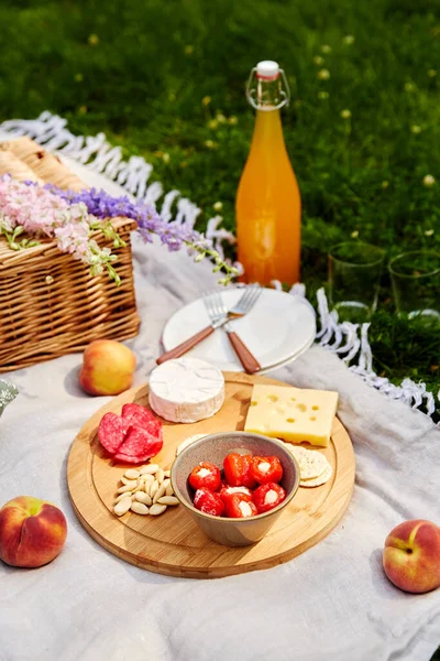 Essen, Getränke und Korb auf Picknickdecke im Gras — Stockfoto