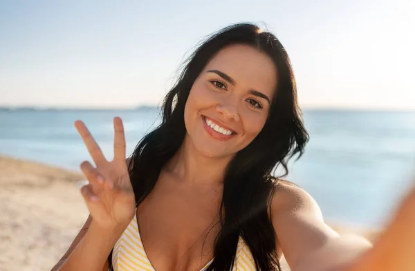Усміхнена жінка в бікіні бере селфі на пляжі — стокове фото