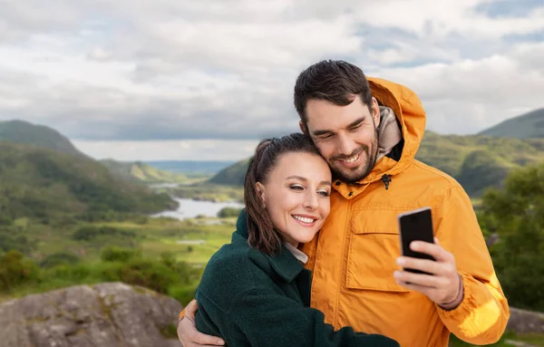 Çift telefonda İrlanda manzarası üzerinden selfie çekiyor. — Stok fotoğraf