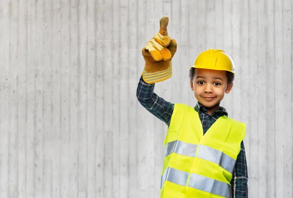 Gutt i konstruksjonshjelm som peker finger opp – stockfoto