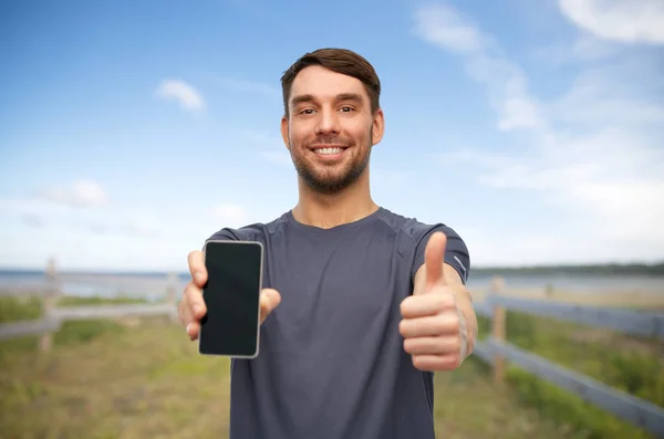 Hombre sonriente en ropa deportiva mostrando teléfono inteligente — Foto de Stock