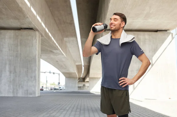 Счастливый человек в спортивной одежде с бутылкой и полотенцем — стоковое фото