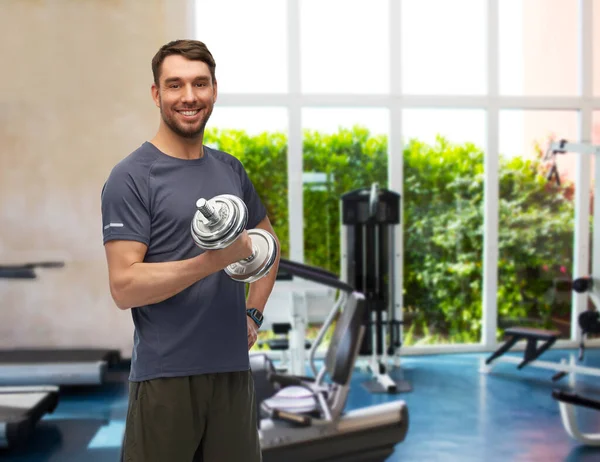 Feliz hombre sonriente haciendo ejercicio con pesas en el gimnasio — Foto de Stock
