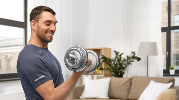 Uomo sorridente che si esercita con i manubri a casa — Foto Stock