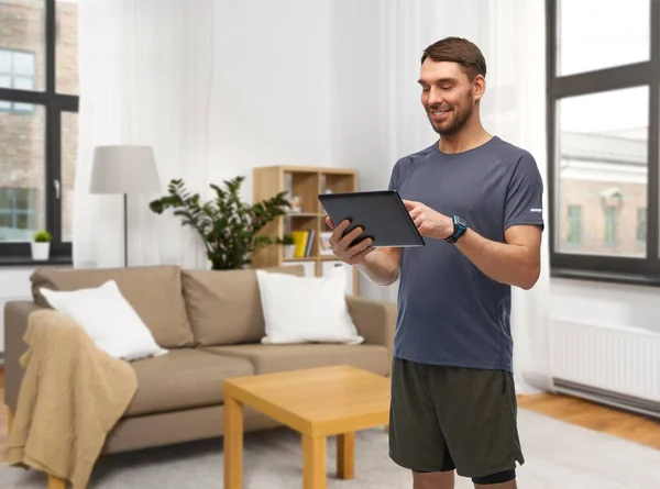 Щасливий чоловік у спортивному одязі з планшетним ПК вдома — стокове фото