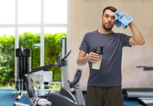 Zmęczony człowiek z butelką i ręcznikiem na siłowni — Zdjęcie stockowe