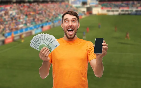 Happy laughing man holding smartphone and money — Stock Photo, Image