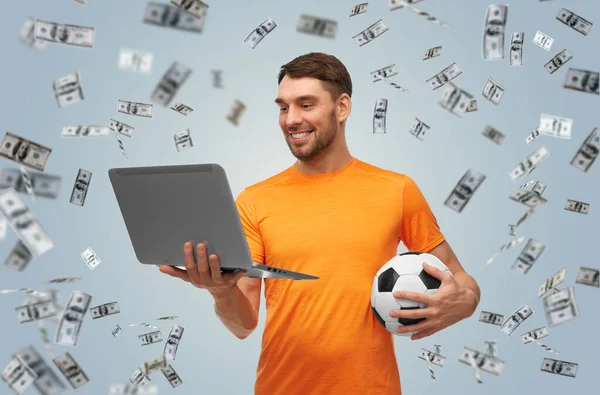 Hombre con pelota de fútbol y portátil sobre el dinero — Foto de Stock